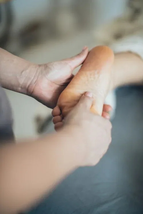 Close-up of a therapist massaging a client’s foot and ankle