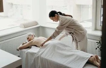 A female therapist performing a full-body massage on a treatment table
